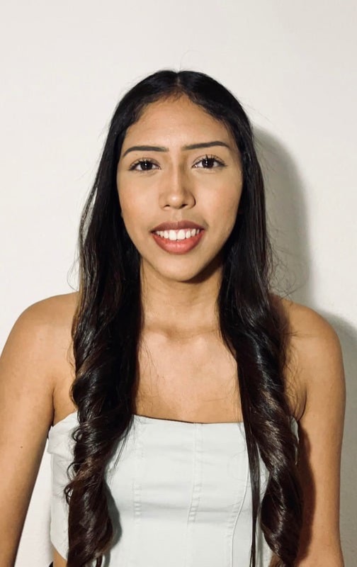Andrea Santacruz sonriendo, con vestido blanco, sobre fondo claro