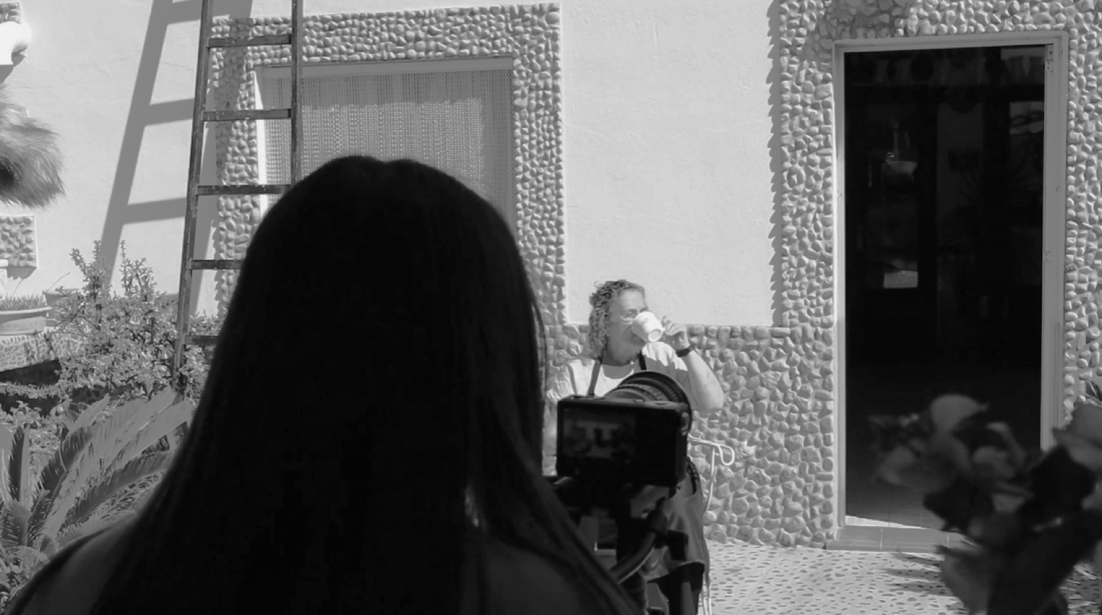 Andrea de espaldas operando la cámara en un rodaje, en blanco y negro